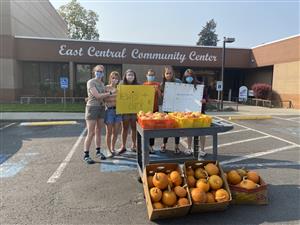 Students standing outside the East Central Community Center with crates of fruit 